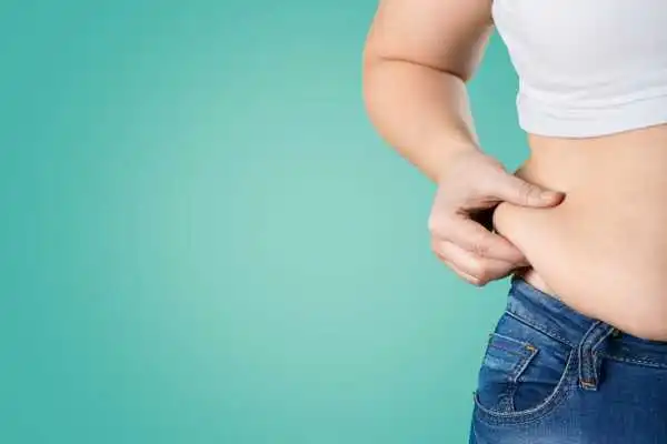 Image of woman pinching her love handles to show weight gain Witley